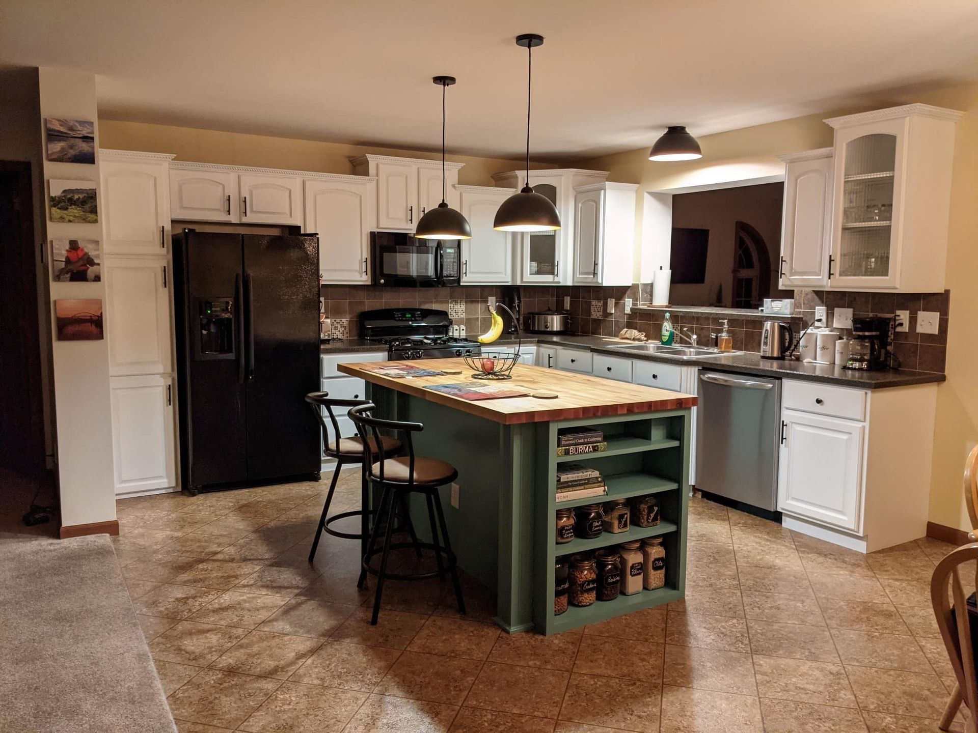 A kitchen with a green island and white cabinets