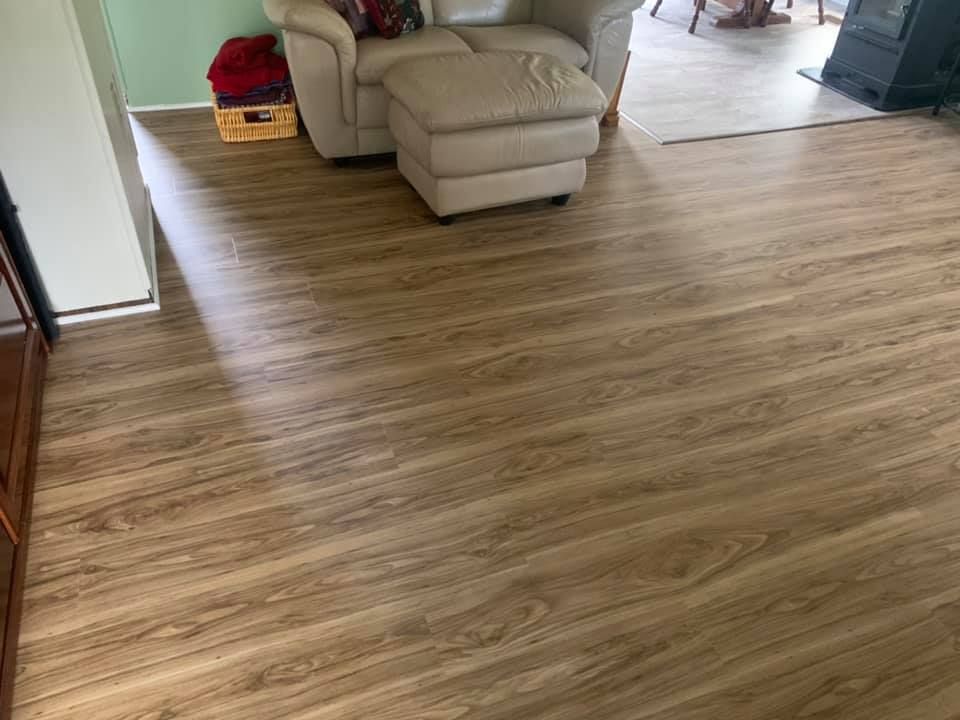A living room with hardwood floors and a chair and ottoman.