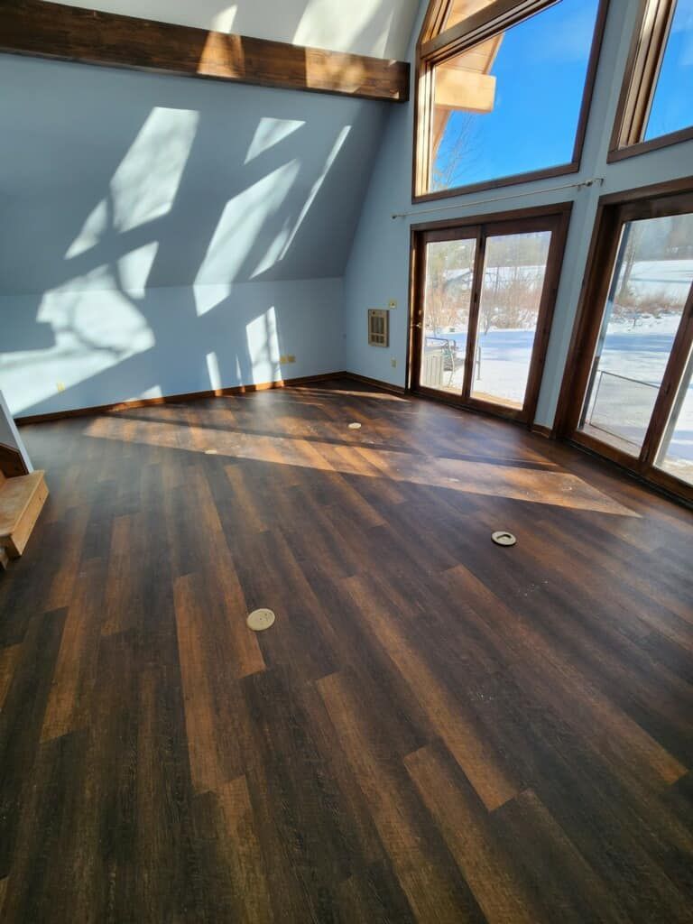 A large empty room with hardwood floors and lots of windows.