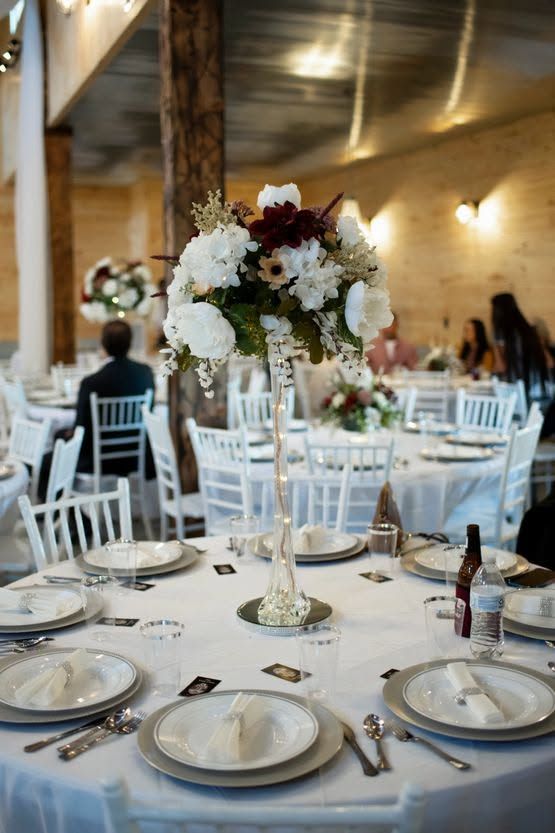 Elegant banquet table with white chairs and floral centerpiece in a warmly lit reception hall