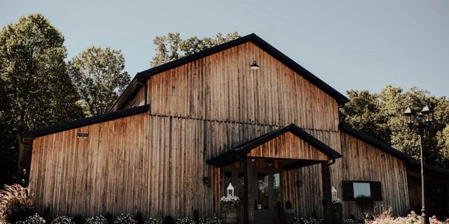 Rustic wooden barn with a peaked roof surrounded by trees under a clear sky