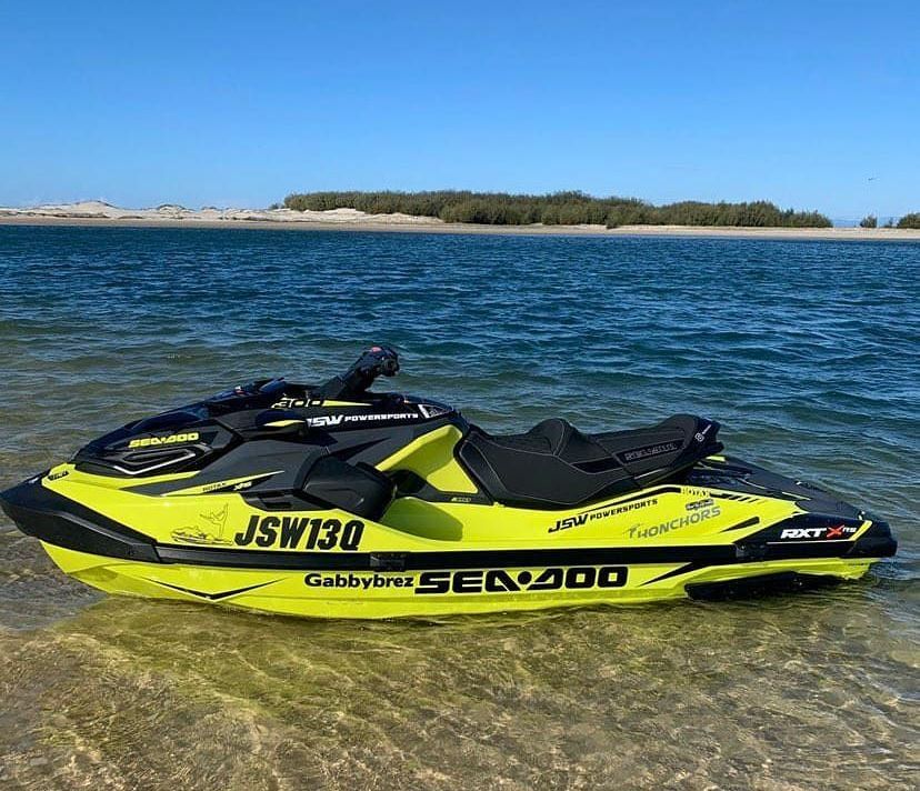 A yellow and black jet ski is parked on the shore of a lake.