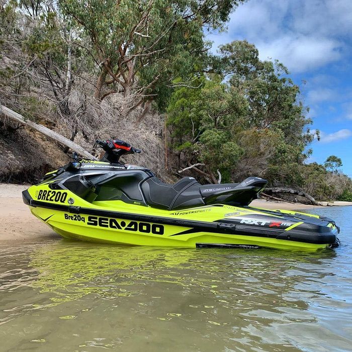 A yellow and black jet ski is parked in the water near a beach.