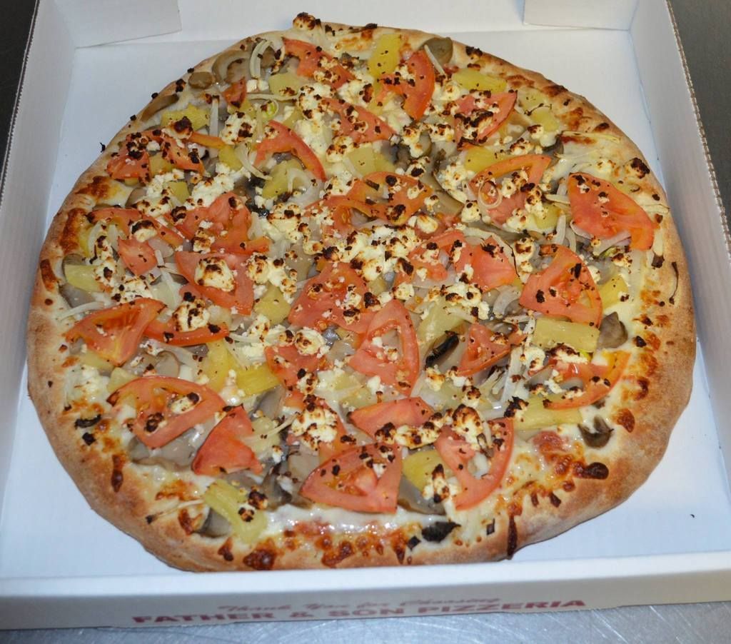 Pizza with pineapple, tomato, mushroom, and cheese in a pizza box.
