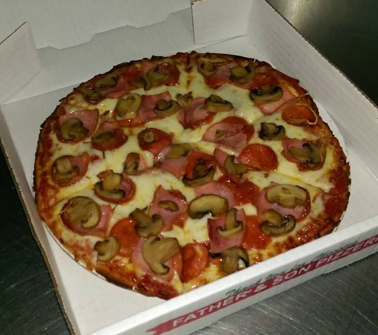 Pizza with mushrooms, ham, and pepperoni in a white box.