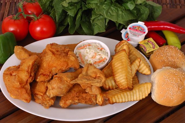A white plate topped with broaster chicken, french fries, coleslaw, and a bun.