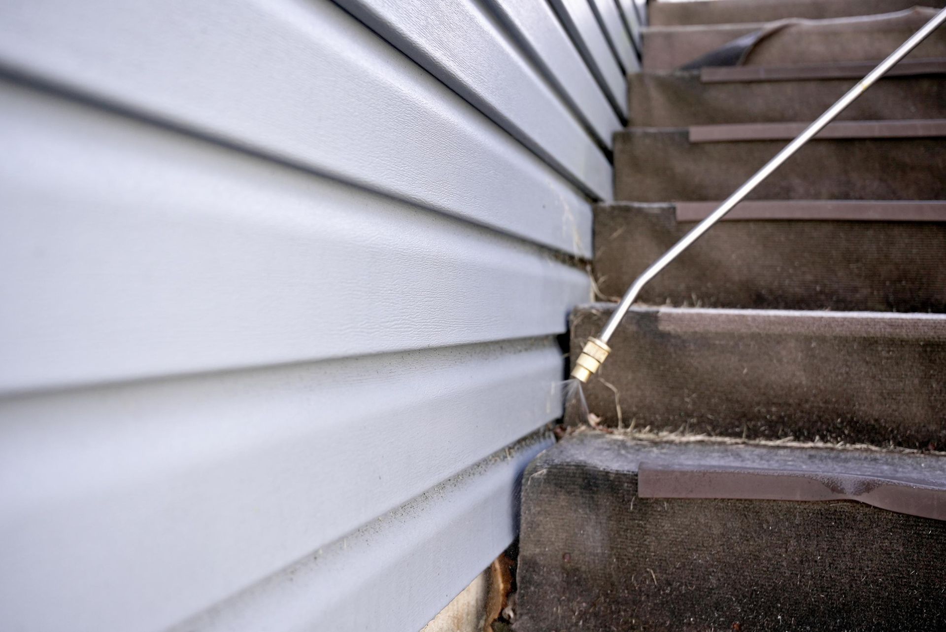 House siding meets concrete stairs with a white cable running across the corner.