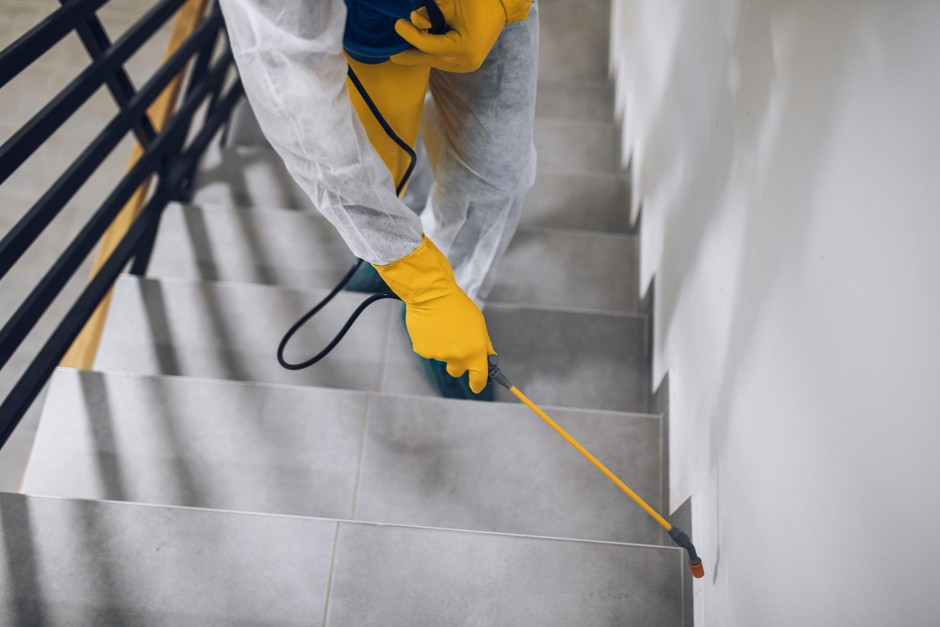 Person in yellow gloves measuring stair steps with a tape measure indoors
