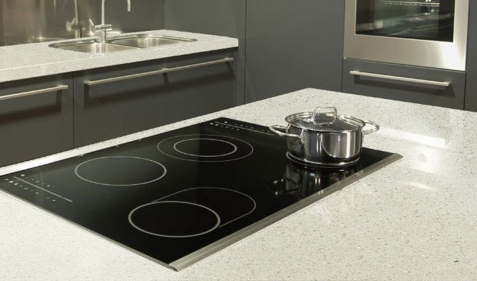 Modern kitchen with black glass cooktop and pot on a light countertop