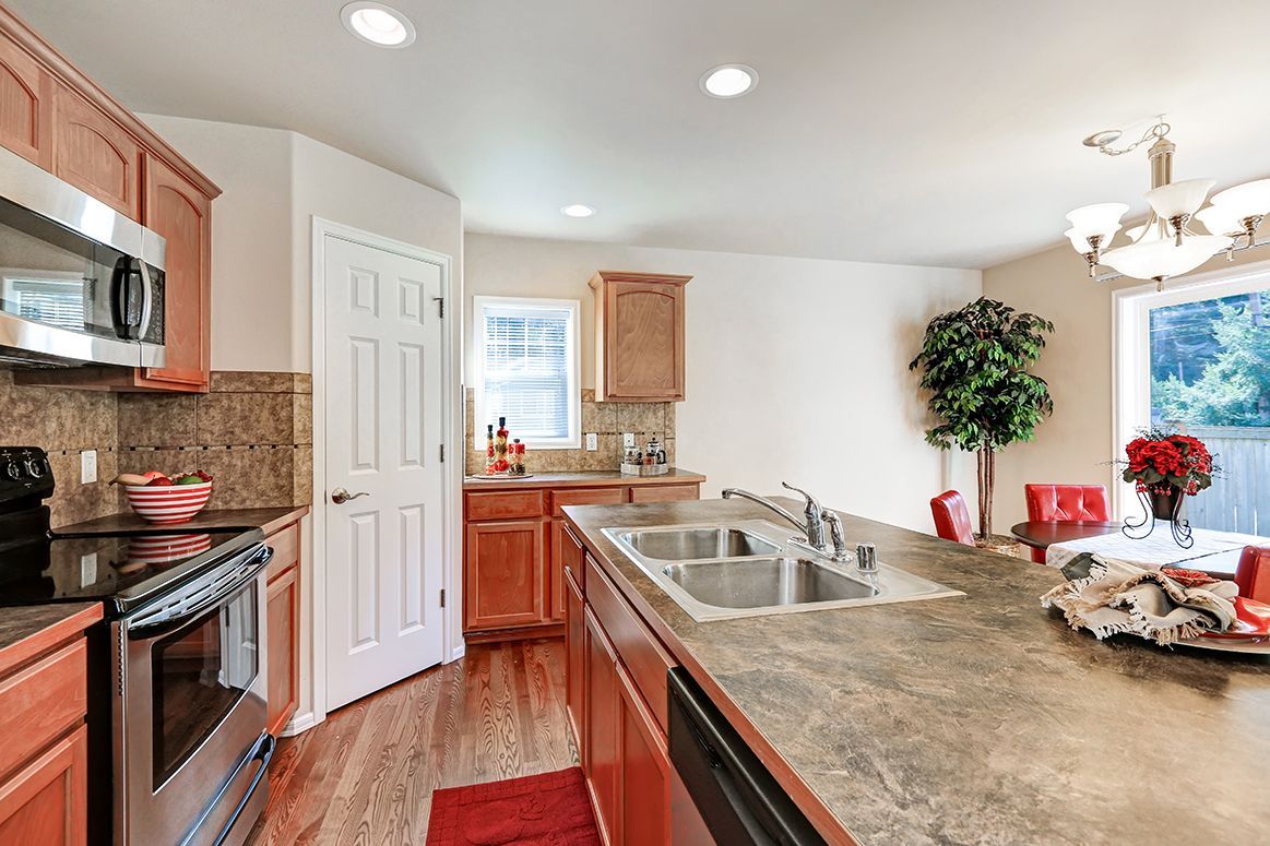 Bright kitchen with wood cabinets, granite island, stainless stove, and a large window