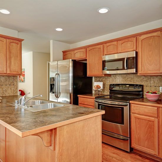 Bright kitchen with wood cabinets, stainless steel appliances, and a central island with sink.
