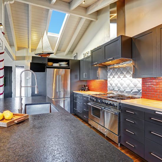 Modern kitchen with dark cabinets, stainless steel appliances, and a large black countertop