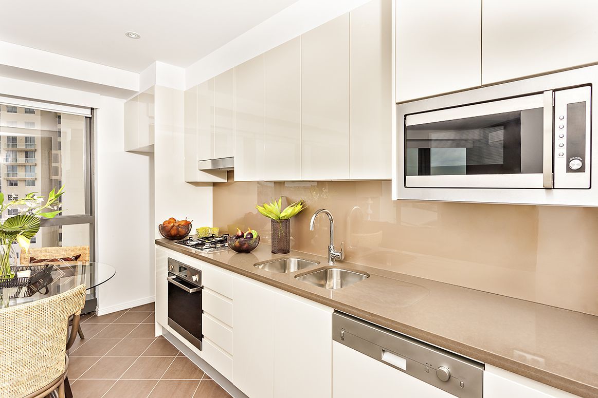 Bright modern kitchen with white cabinets, beige countertops, and stainless steel appliances