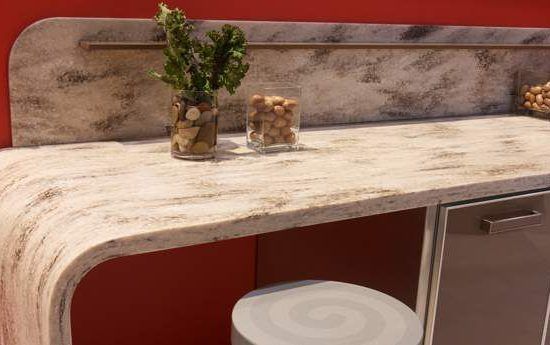 Modern kitchenette with stone countertop, red cabinet, and small plant on the shelf