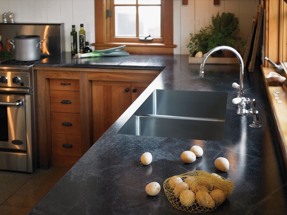 Kitchen countertop with eggs scattered beside a sink and a bowl of eggs in a warm-toned kitchen