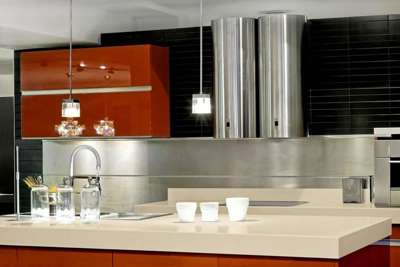 Modern kitchen with red cabinets, stainless steel hood, and a light countertop with glasses and cups