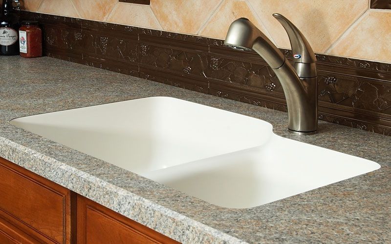 Kitchen countertop with a white double sink and chrome faucet on a speckled granite surface.