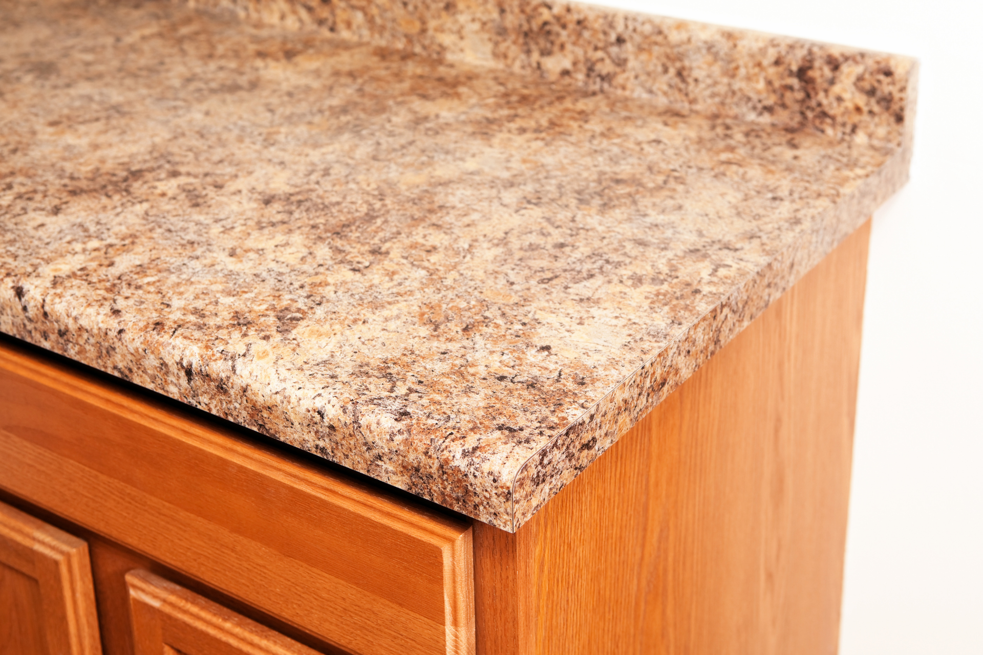 Wooden countertop corner with water damage and a taped, stained backsplash area