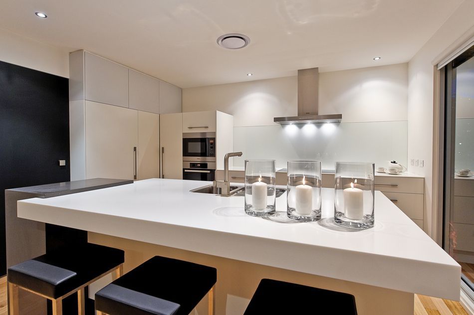 Modern kitchen with a large white island, bar stools, and stainless steel appliances under bright lighting