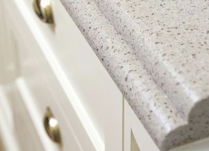 Close-up of a speckled gray countertop edge above white cabinet drawers