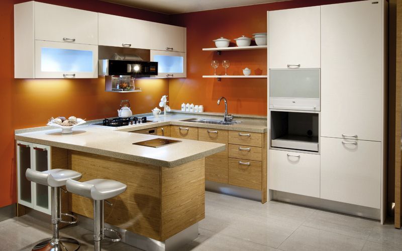 Modern kitchen with white cabinets, orange walls, island seating, and built-in appliances