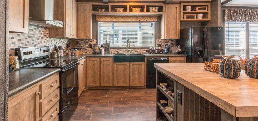 Modern kitchen with wood cabinets, stainless stove, large island, and a window over the sink