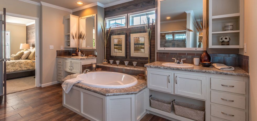 Elegant bathroom with soaking tub, dual sinks, and large mirror in warm neutral tones