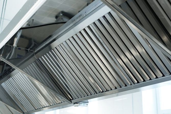 Stainless steel kitchen range hood with vent filters mounted under a cabinet
