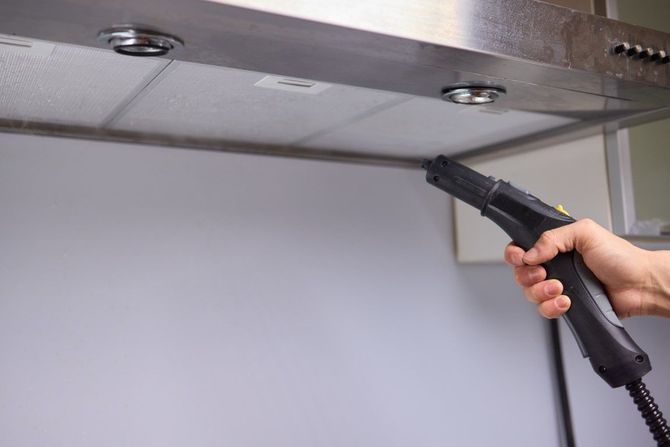 Hand using a handheld vacuum to clean the underside of a metal surface