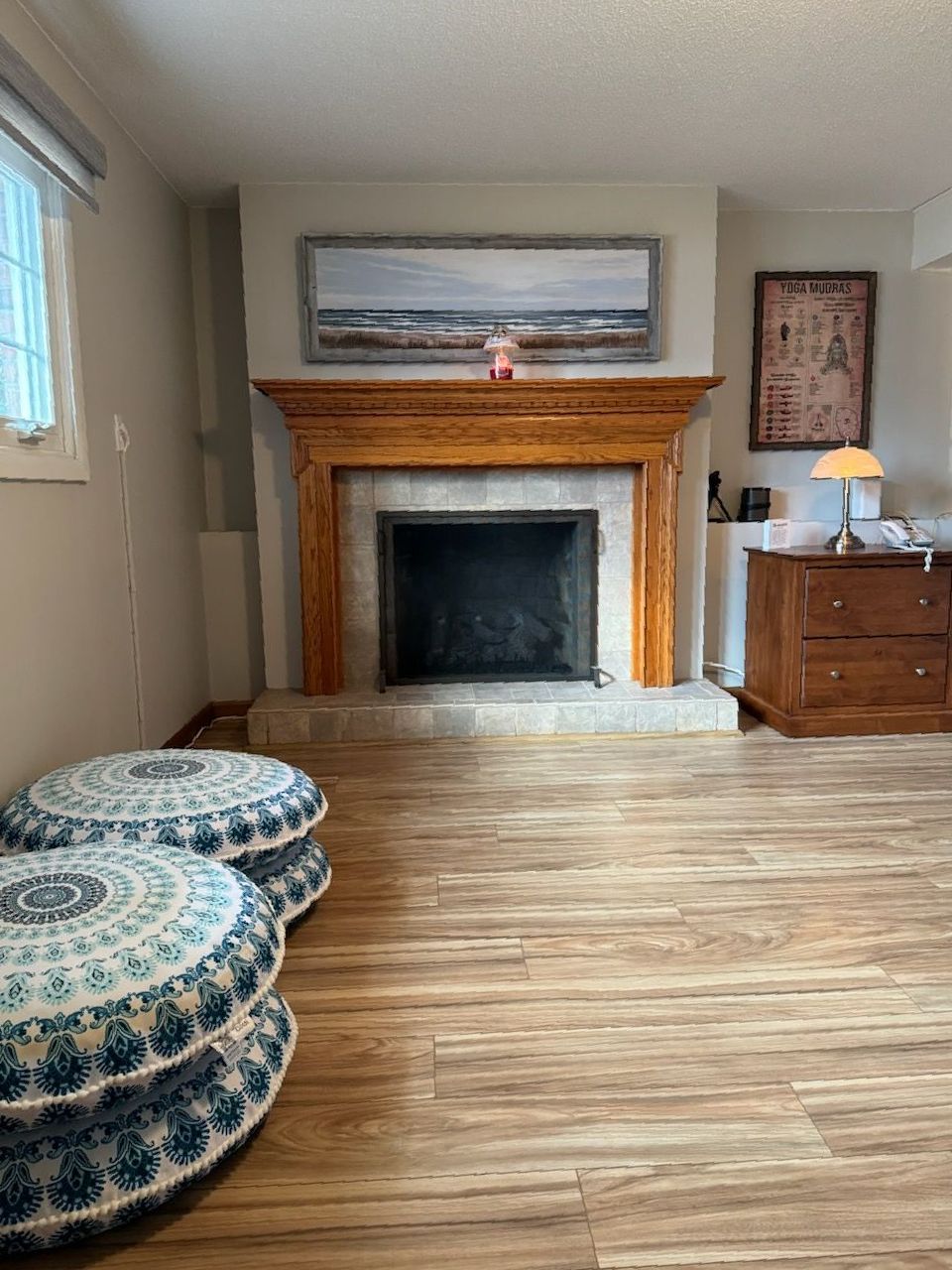 A woman is sitting on a yoga mat in a room.