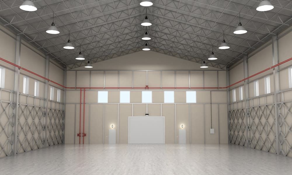A Large Empty Warehouse With Lots of Windows and Ceiling Lights — Watkins Electrical In Pialba, QLD