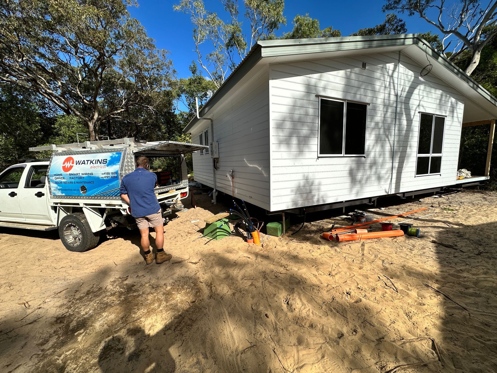 Man by white house, unloading supplies from truck — Watkins Electrical In Maryborough, QLD