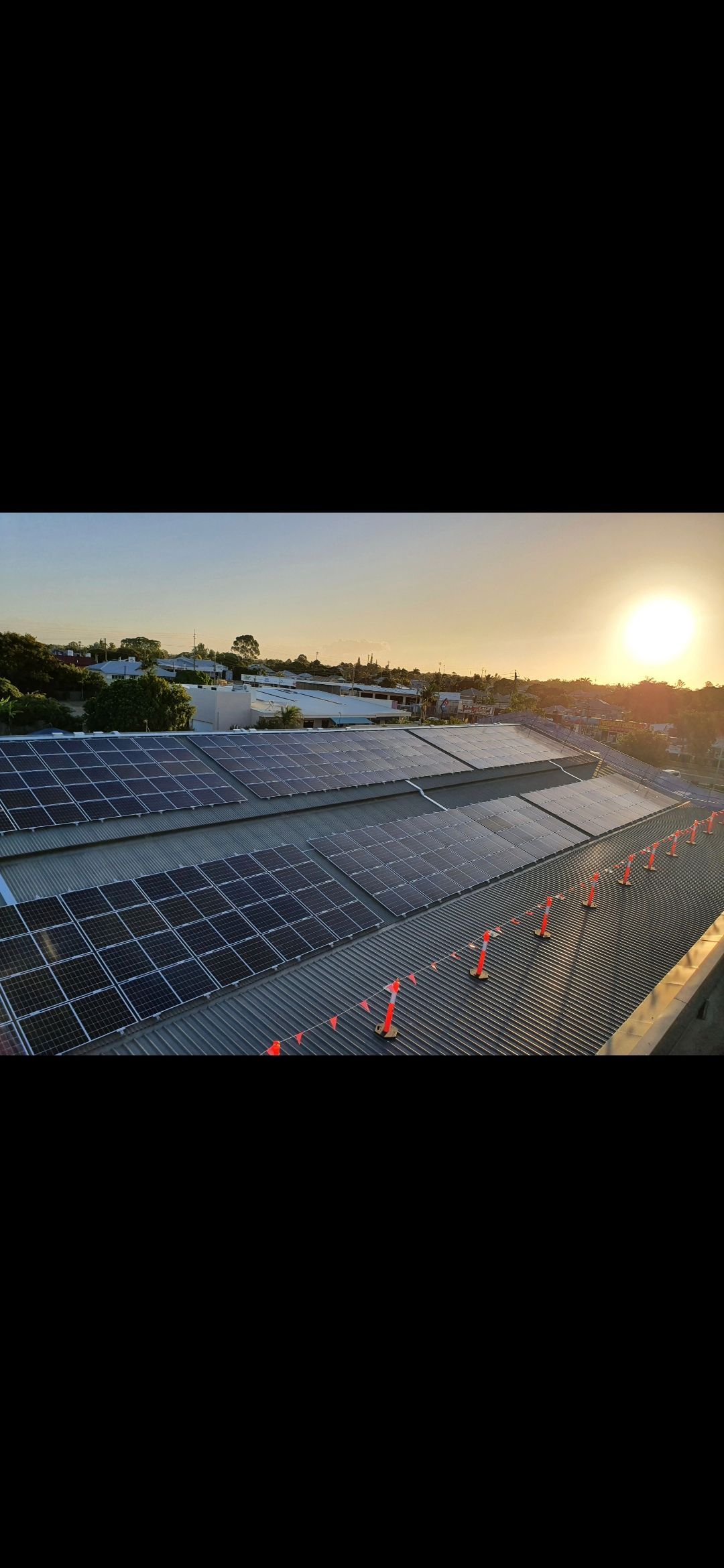 Solar panels in a field at sunset — Watkins Electrical In Maryborough, QLD