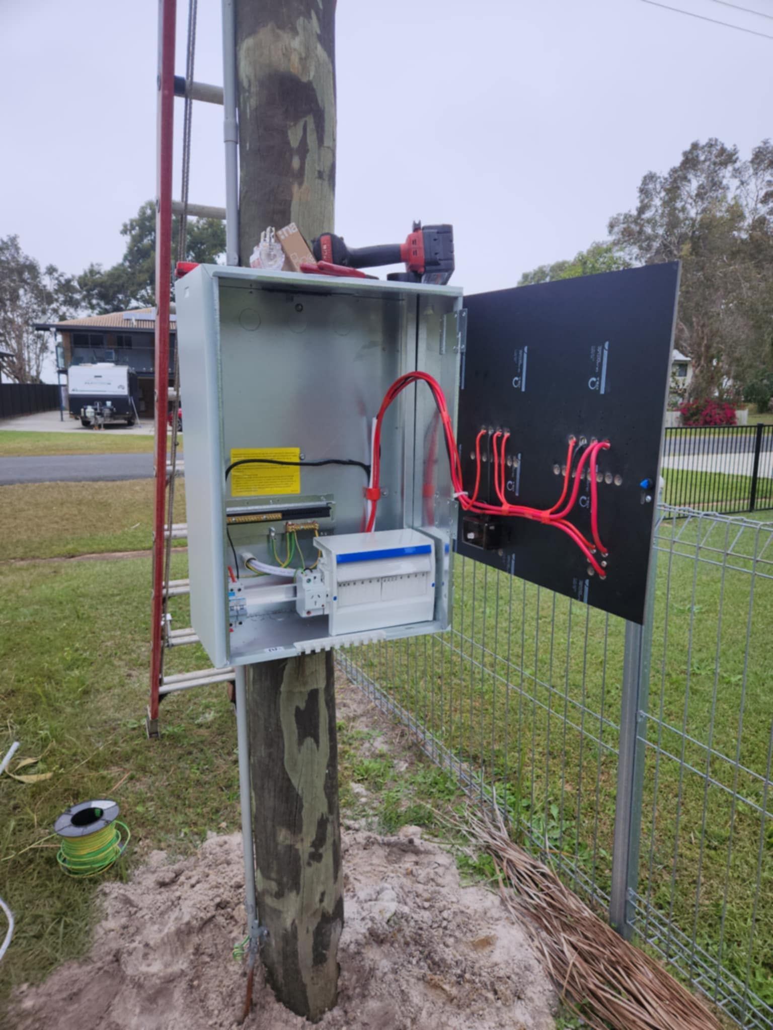 Electrical box open on a utility pole, with red wires and circuit breakers — Watkins Electrical In Maryborough, QLD