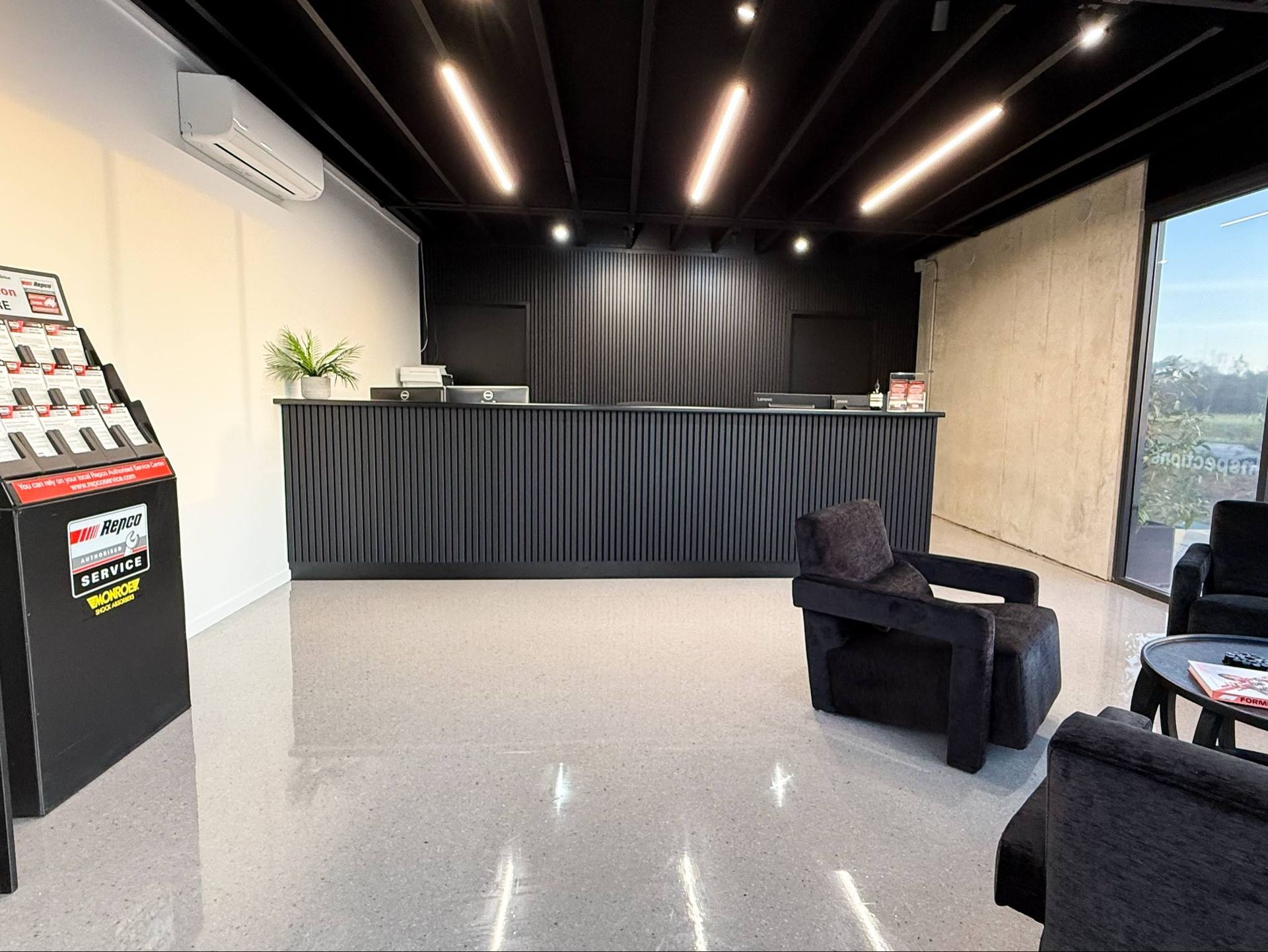 Modern black and white waiting area with reception desk, product display, and chairs. — Watkins Electrical In Fraser Coast, QLD
