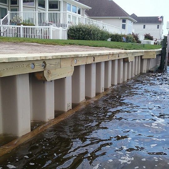 Raised seawall beside waterfront homes with rippling water below