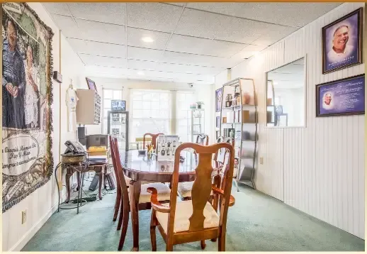 Bright dining room with wooden chairs, glass table, wall art, and a sunlit window