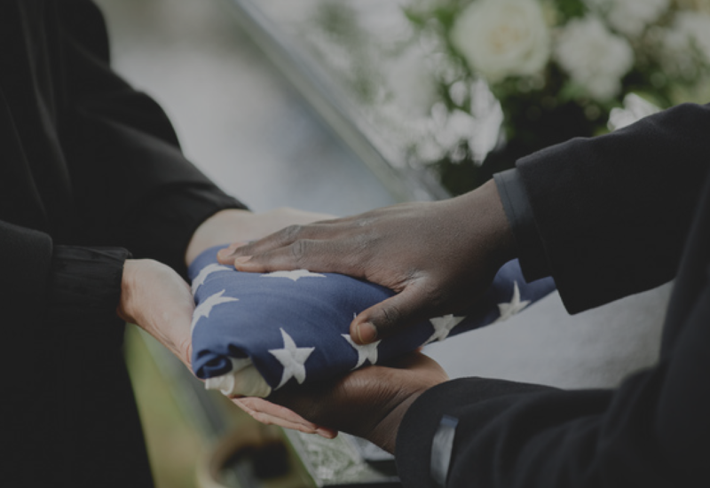Hands folding a folded American flag during a solemn ceremony