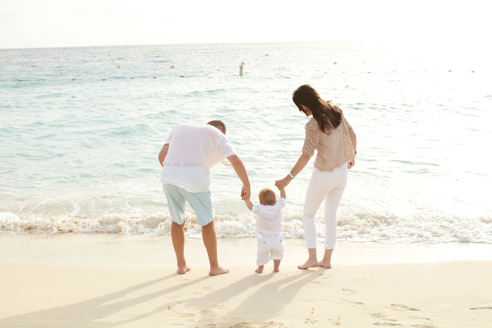 Family holding hands on a sunny beach by the water
