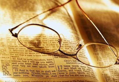 Glasses resting on an open book under warm sepia lighting