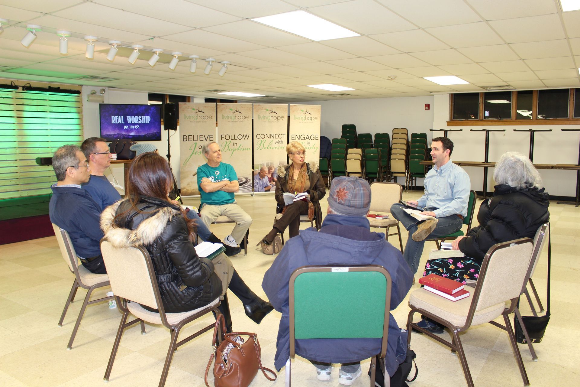 People seated in a circle during a community meeting in a bright room