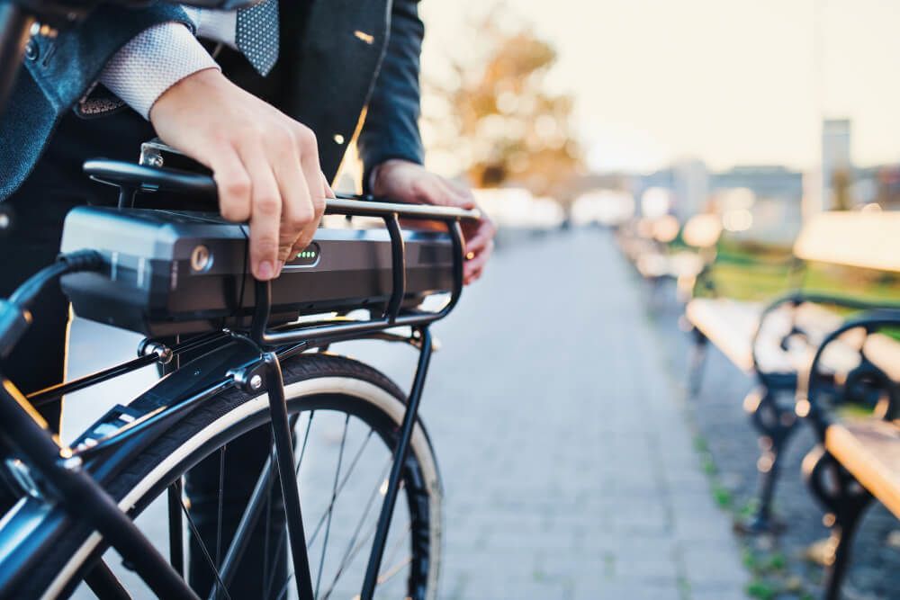 Een man fietst met een accu achterop.