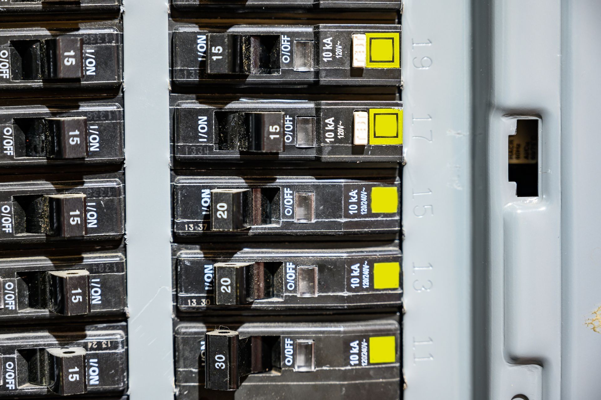 Technician testing electrical panel with digital multimeter and red probes in a wiring cabinet
