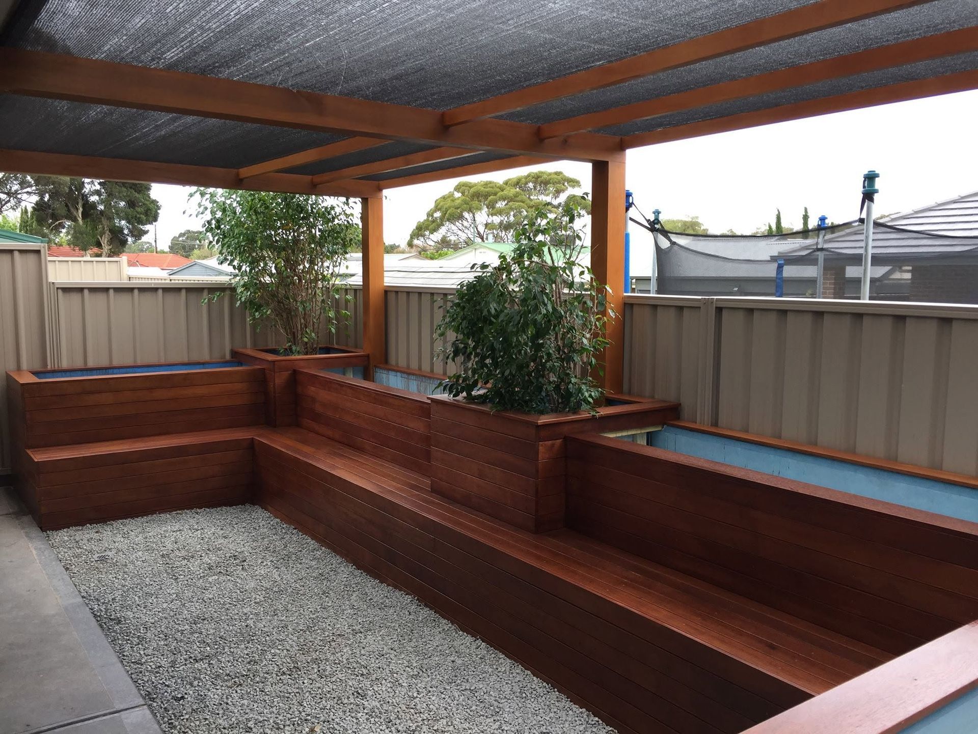 Backyard with green lawn, metal swing set, slide, and a wooden deck beside a fence