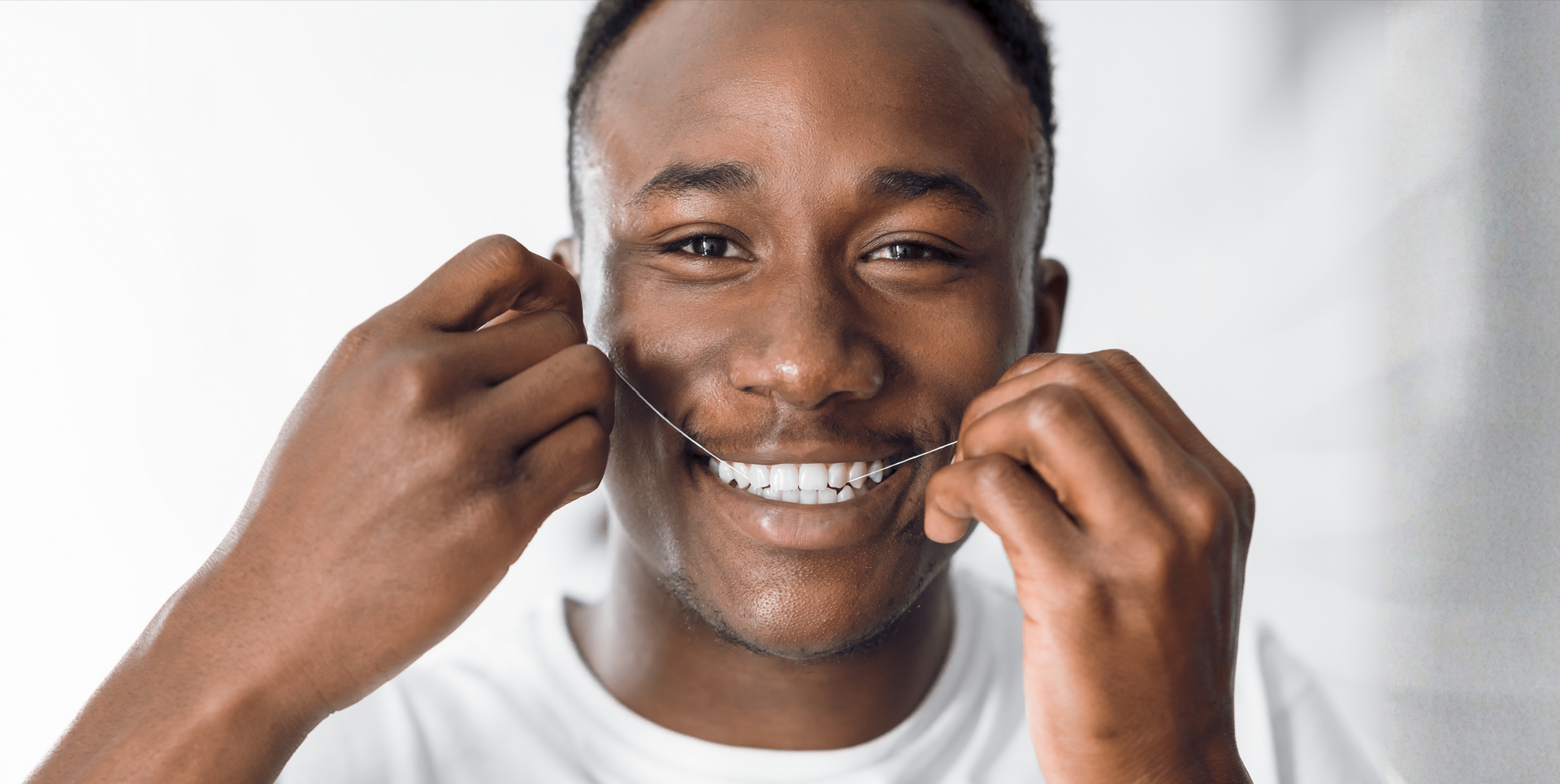 Man flossing his teeth and smiling
