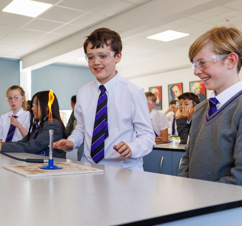 Students taking a test in a classroom, seated at desks and writing quietly.