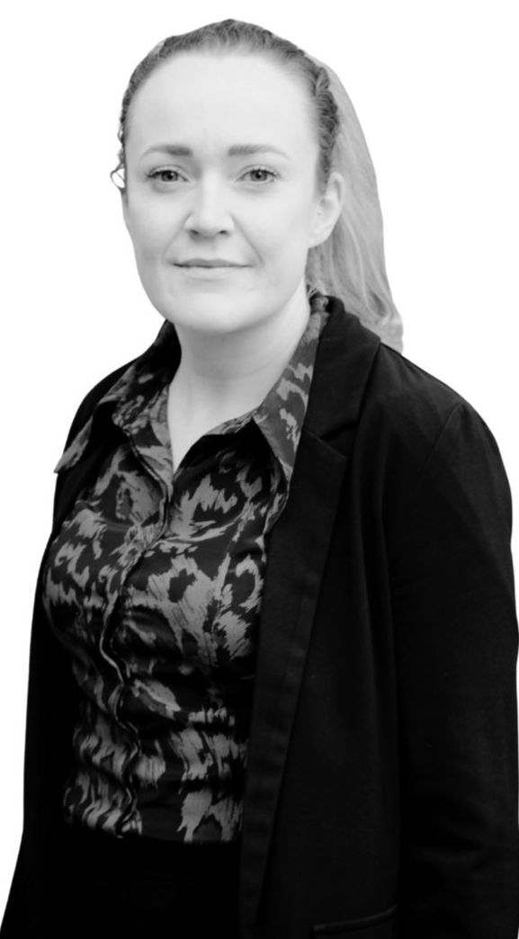Portrait of a woman in a patterned blouse and dark jacket against a plain white background