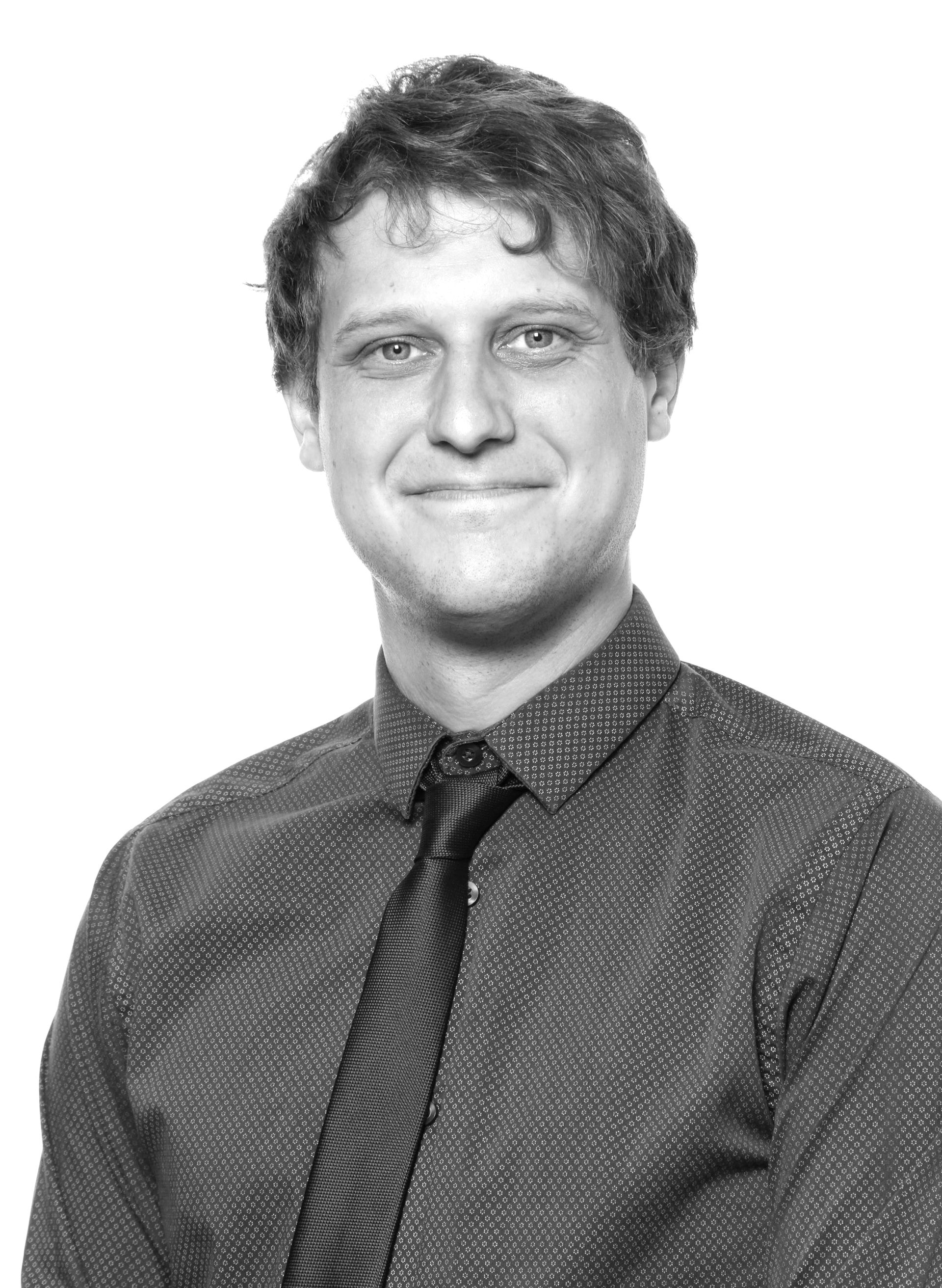 Smiling person in glasses and a blazer against a plain white background