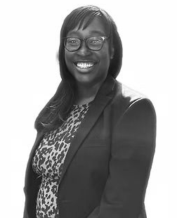 Smiling person in glasses and a blazer against a plain white background
