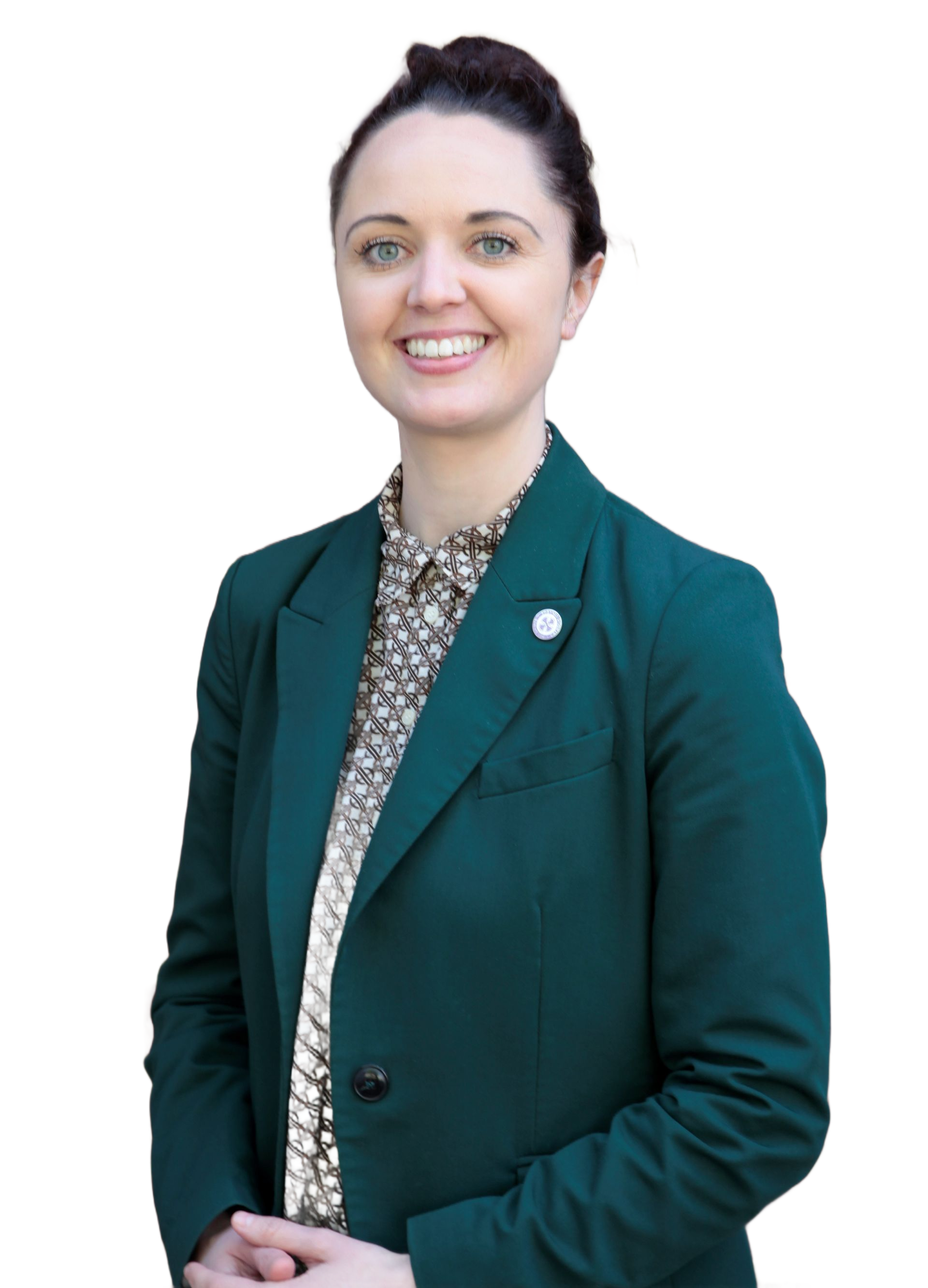 Smiling person in a light blazer over a dark top, standing against a plain background.